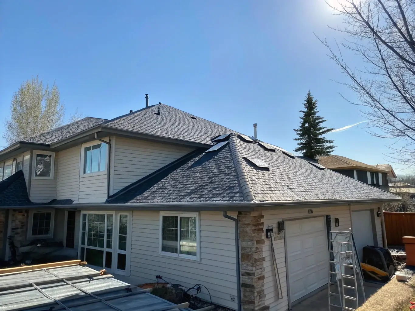 A recently completed roofing project by JDI Contracting, showcasing new asphalt shingles and impeccable installation, set against a clear blue sky.